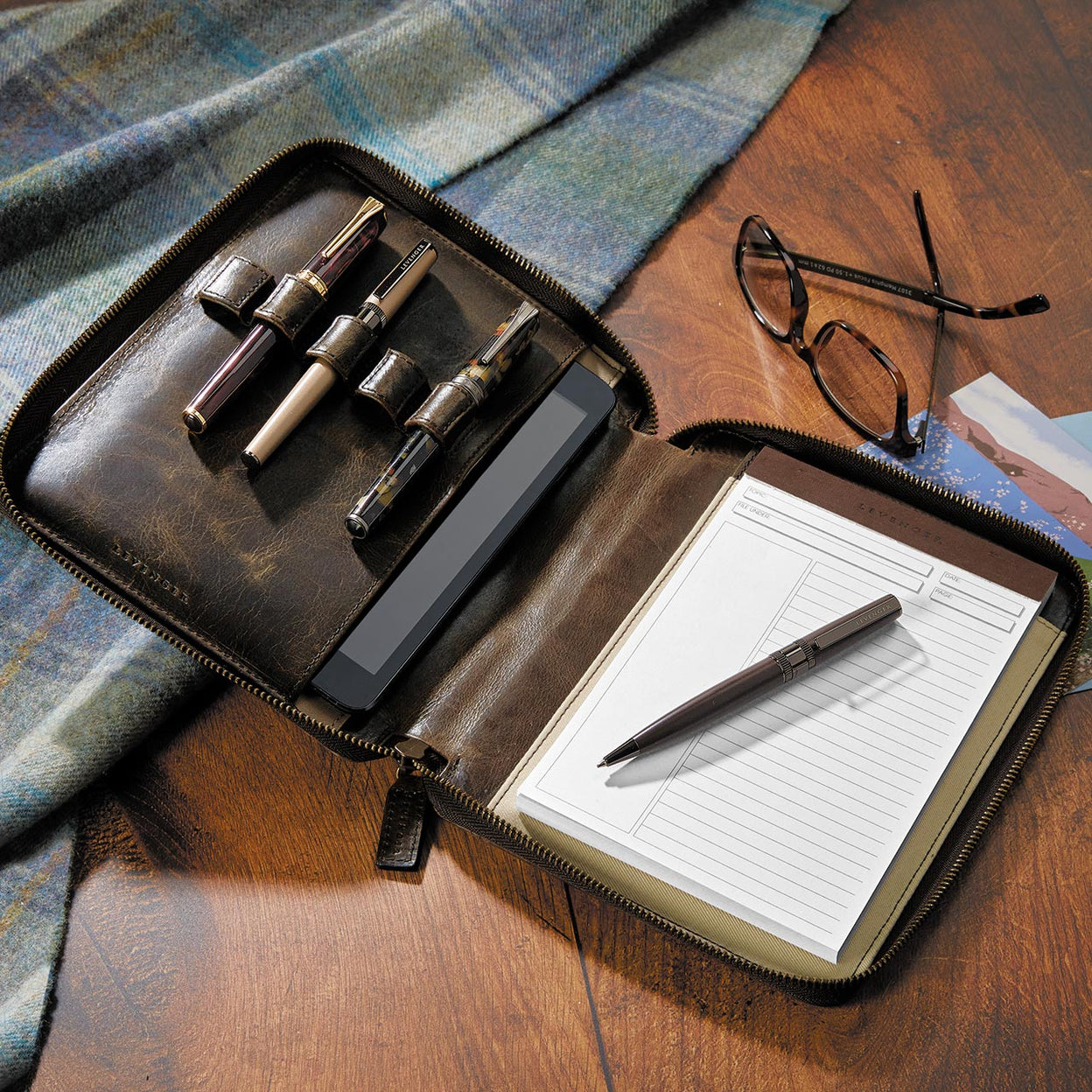 A compact Circa notebook with tab and pocket dividers arranged on a boarding pass, passport, and pen—ready for airport security.