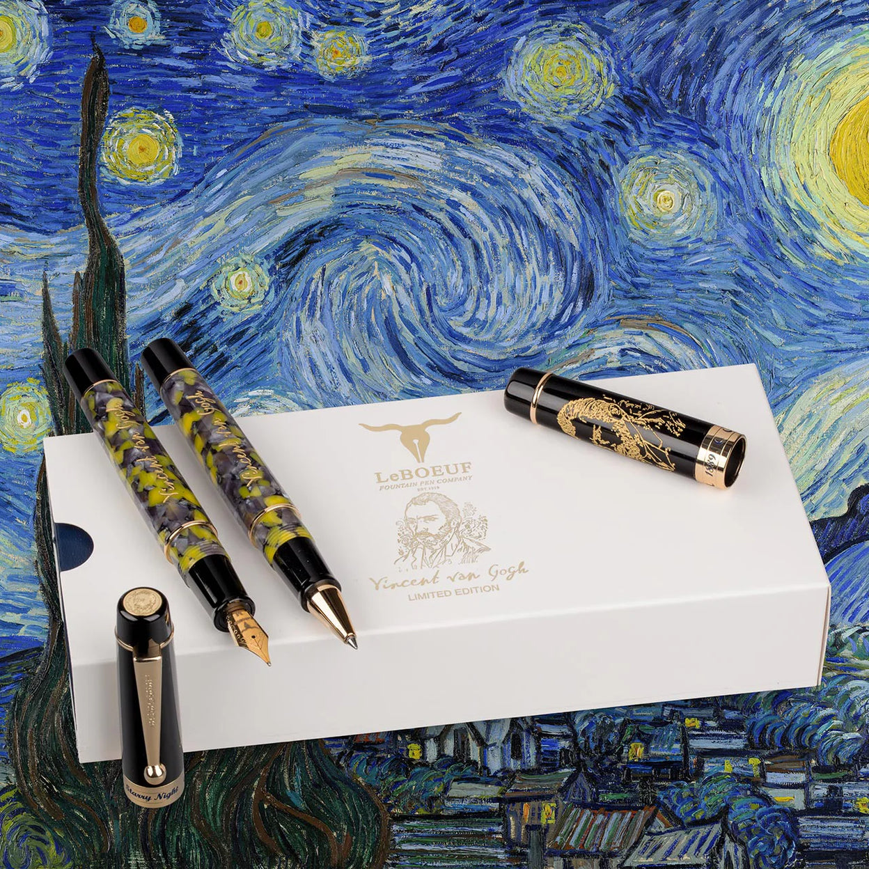 A curated row of Levenger pens in contrasting finishes—sleek black, marble green, bright confetti, and brushed silver—resting on a notebook and gift box ribbon.