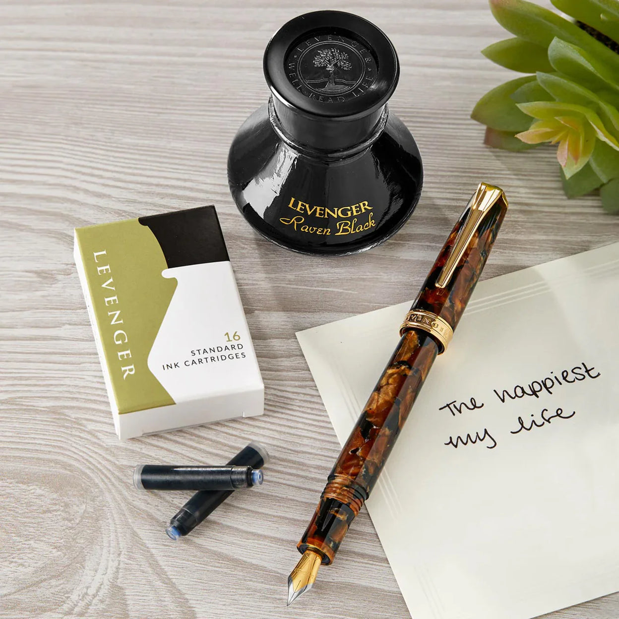 A well‑loved fountain pen, rollerball, and ballpoint arranged beside assorted refills and a soft cloth, ready for maintenance.
