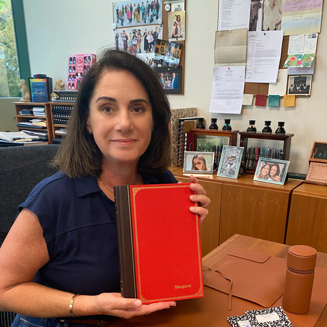 A letter-size leather folio opened on a conference table, showing a Circa page with Topic, Highlights, and Actions filled in, plus a pen and a few color-coded tabs.