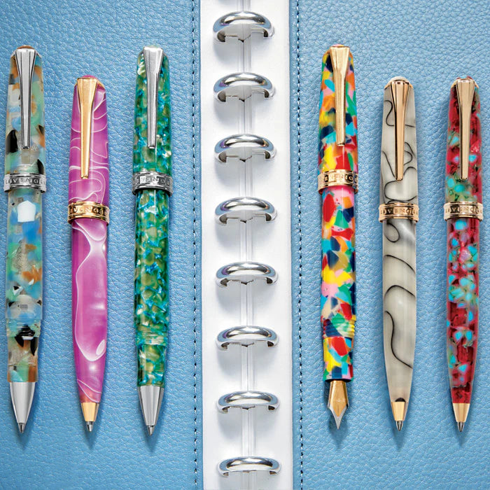 A curated capsule pen collection on a tidy desk: a rollerball, ballpoint, and fountain pen beside a leather pen case and a small wooden pen studio with an ink bottle.