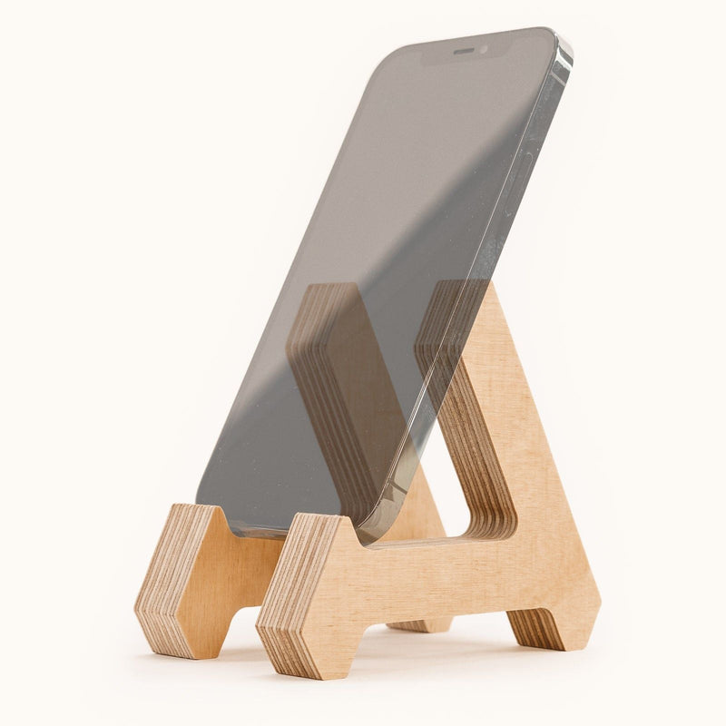 Phone sits on the Birch Phone Stand with the natural wood design on a light backdrop