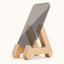 Phone sits on the Birch Phone Stand with the natural wood design on a light backdrop