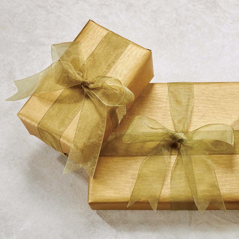 Gold gift boxes wrapped with sheer gold ribbons on a light surface